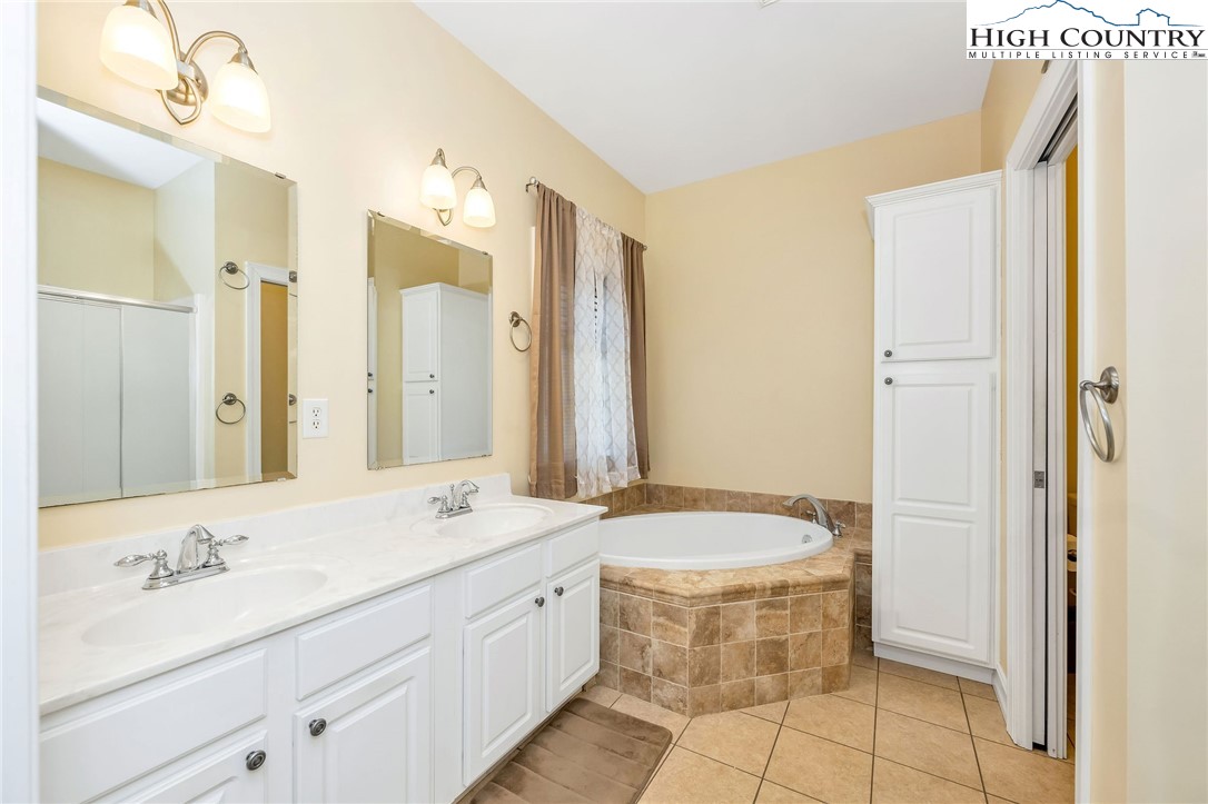 3186-3190 Silas Creek Road Lansing, NC 28643 - Photo 21 of 50 a bathroom with a double vanity sink a mirror and a bathtub