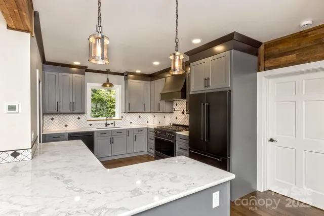 a kitchen with stainless steel appliances kitchen island granite countertop a refrigerator a sink a stove and a wooden floors