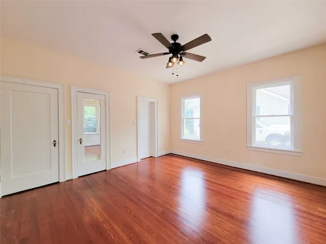 a view of an empty room with wooden floor and a window