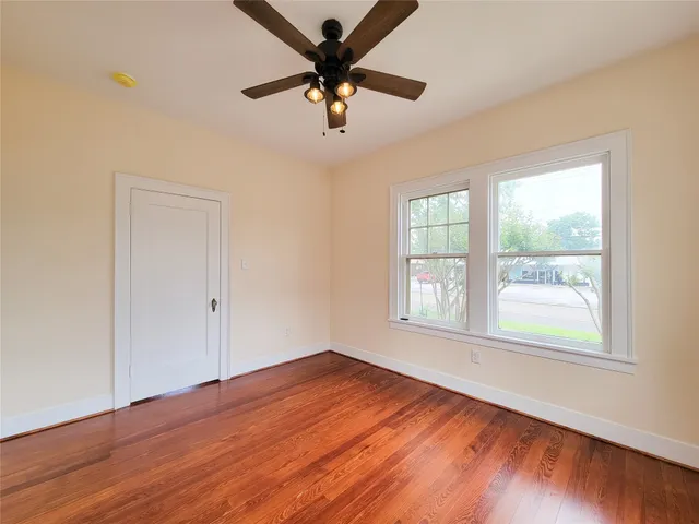 a view of an empty room with wooden floor and a window