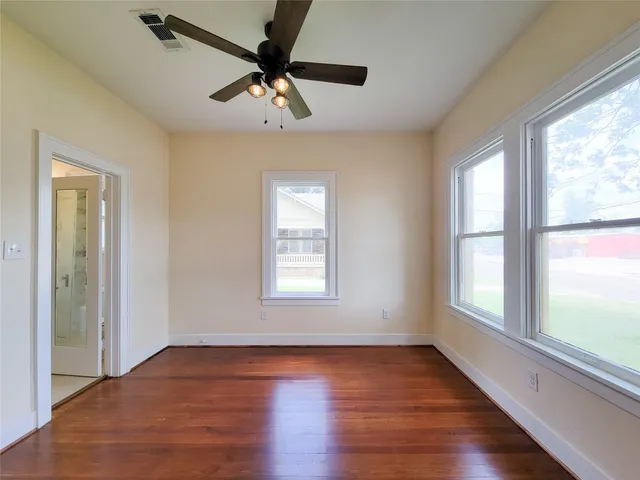 a view of an empty room with wooden floor and a window