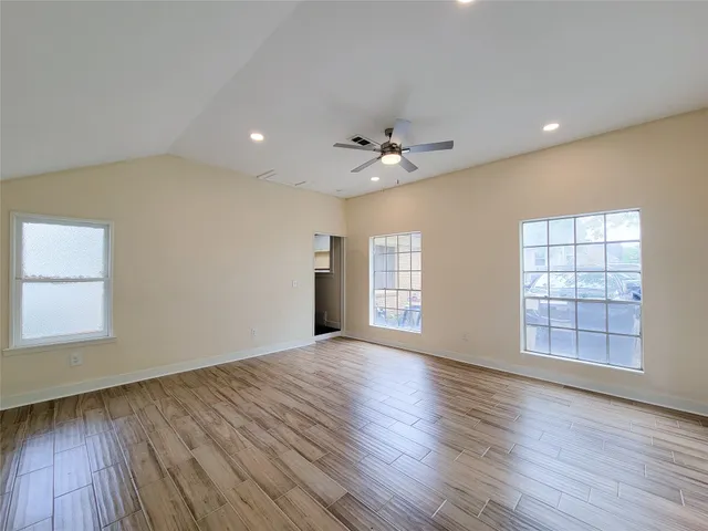 an empty room with wooden floor and windows