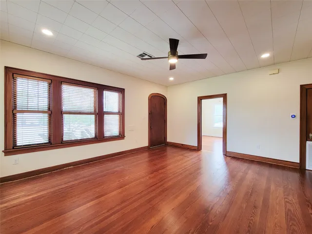 a view of an empty room with window and wooden floor
