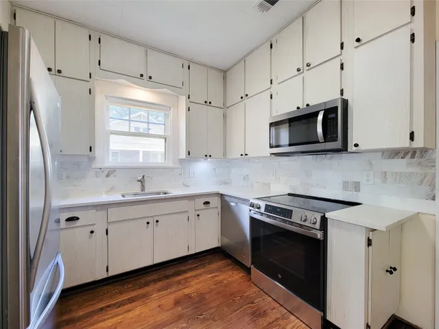 a kitchen with stainless steel appliances granite countertop white cabinets granite counter tops and a window