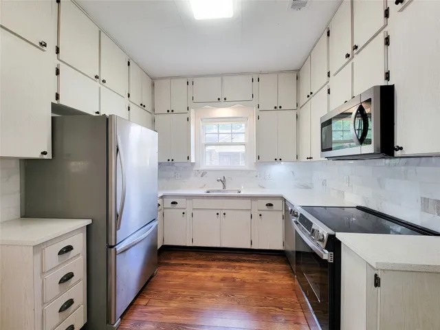 a kitchen with white cabinets and stainless steel appliances