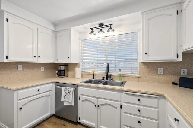 a kitchen with cabinets appliances a sink and a window