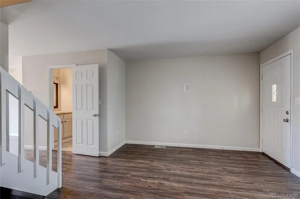 a view of an empty room with wooden floor and door