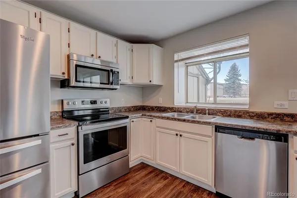 a kitchen with white cabinets appliances and window