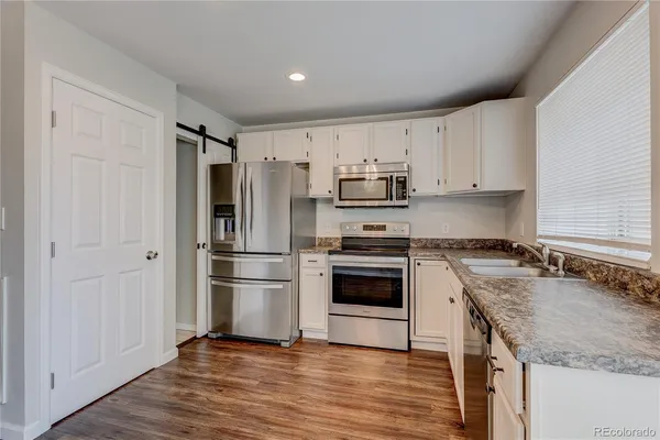 a kitchen with kitchen island granite countertop a sink cabinets and stainless steel appliances