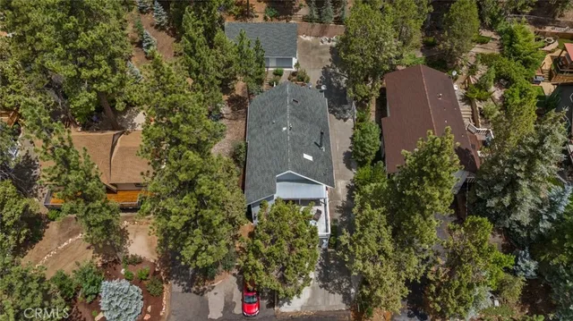 an aerial view of a house with a yard and trees all around