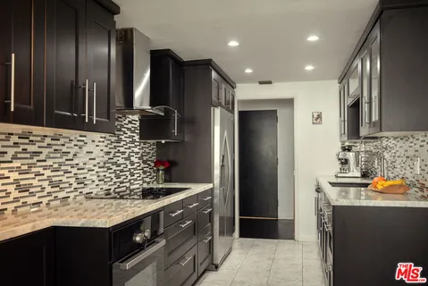 a kitchen with stainless steel appliances kitchen island granite countertop a refrigerator and a sink