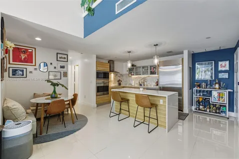 a living room with stainless steel appliances kitchen island granite countertop furniture and a dining table with bookshelf