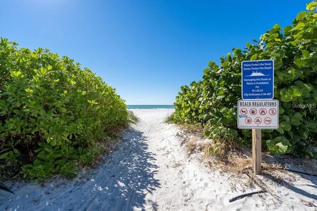 a sign board with a house in the background