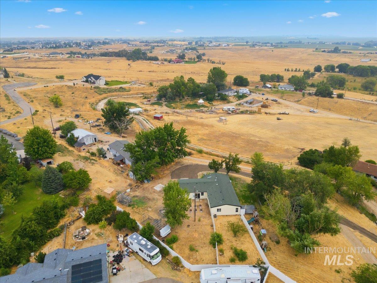 17114 Goodson Road Caldwell, ID 83607 - Photo 44 of 47 Expansive property featuring a single-story residence with a dark green roof, a white perimeter fence, and surrounding natural landscaping