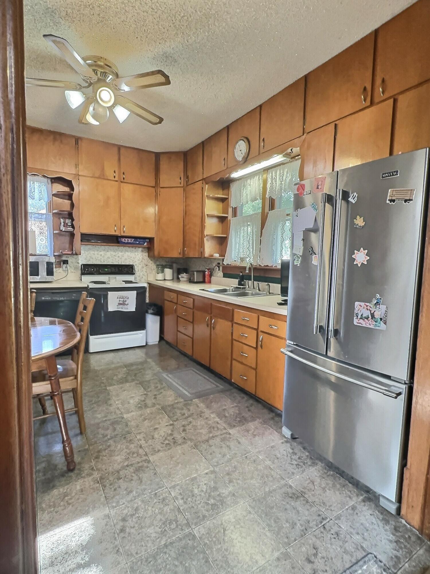 136 East Main Street Brook, IN 47922 - Photo 14 of 25 a kitchen with stainless steel appliances granite countertop a refrigerator a sink a stove and white cabinets