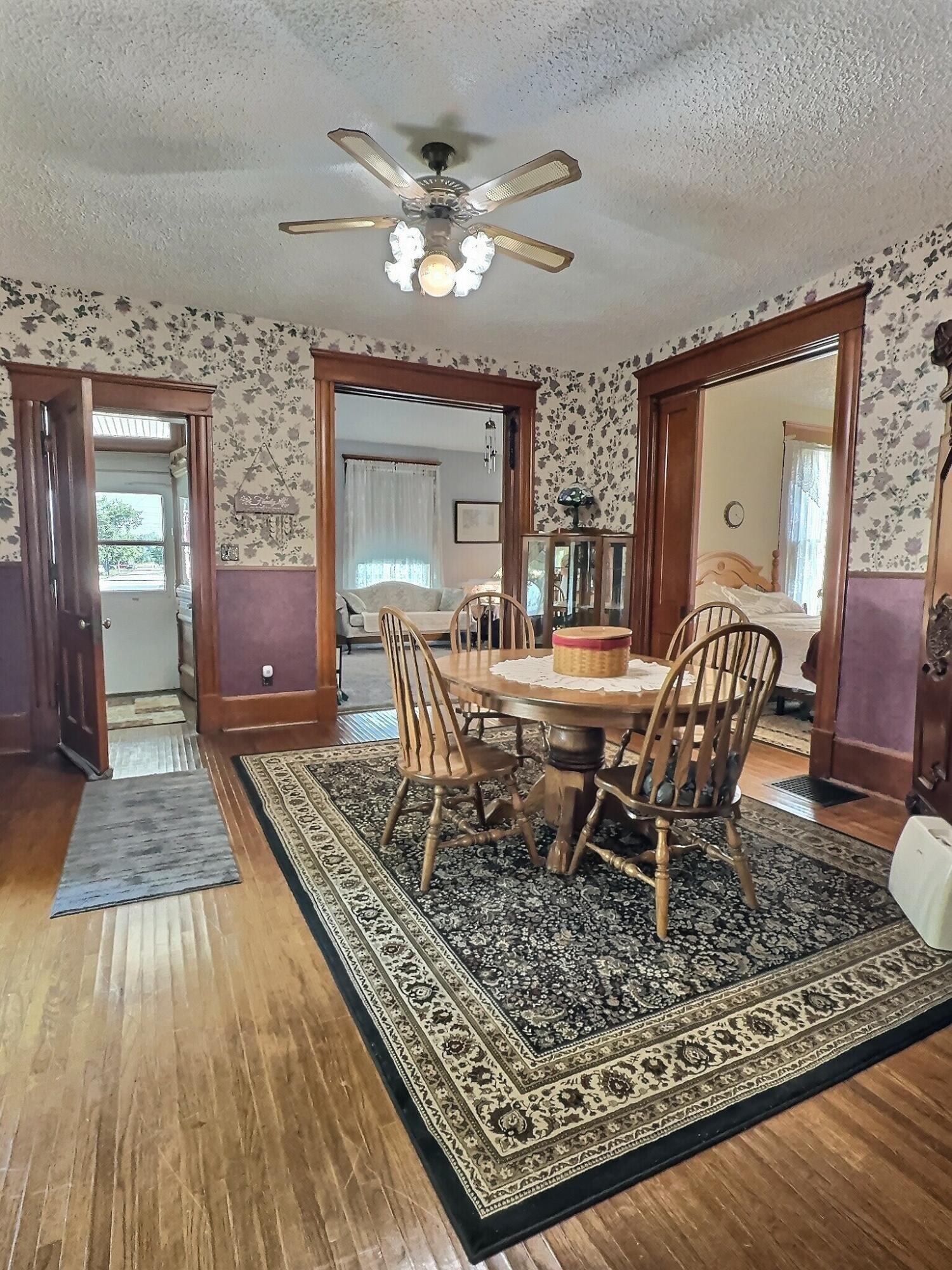 136 East Main Street Brook, IN 47922 - Photo 17 of 25 a dining room with wooden floor a chandelier fan a wooden table and chairs