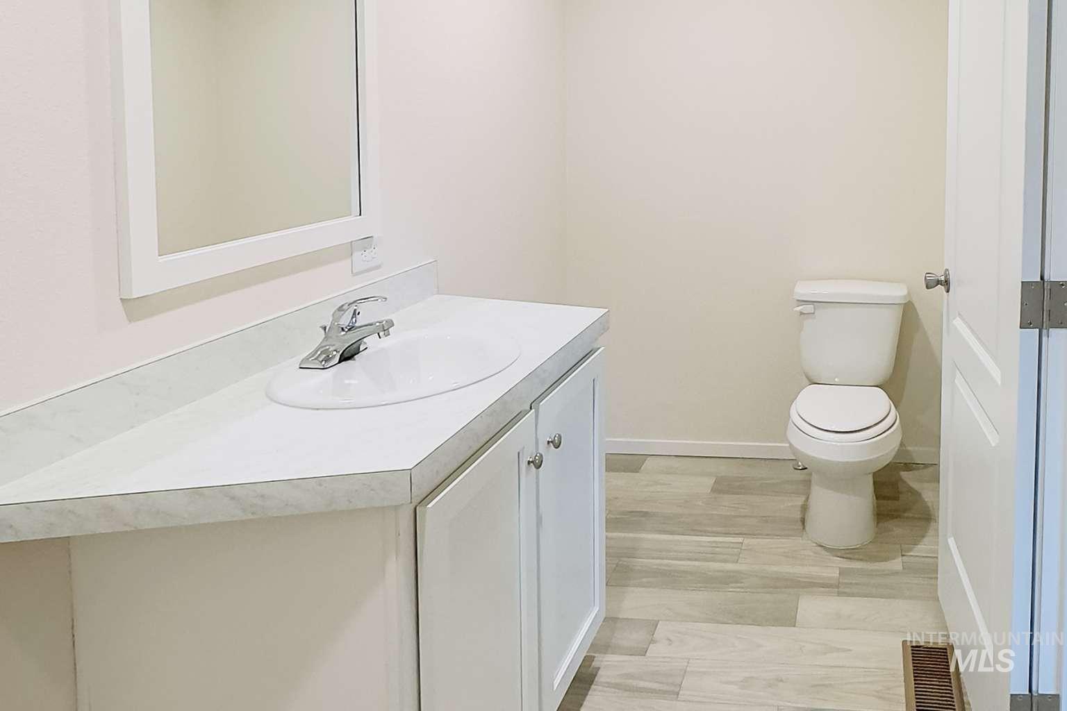 10 Kamloop Lane Orofino, ID 83544 - Photo 10 of 17 Bathroom featuring a white vanity with an integrated sink, framed mirror, and wood-finish flooring