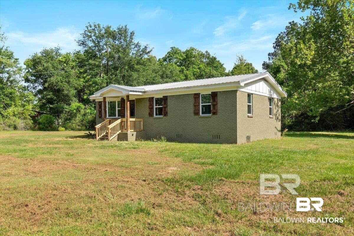 29397 Loper Road Loxley, AL 36551 - Photo 2 of 22 View of front facade featuring crawl space, brick siding, a front yard, and view of scattered trees