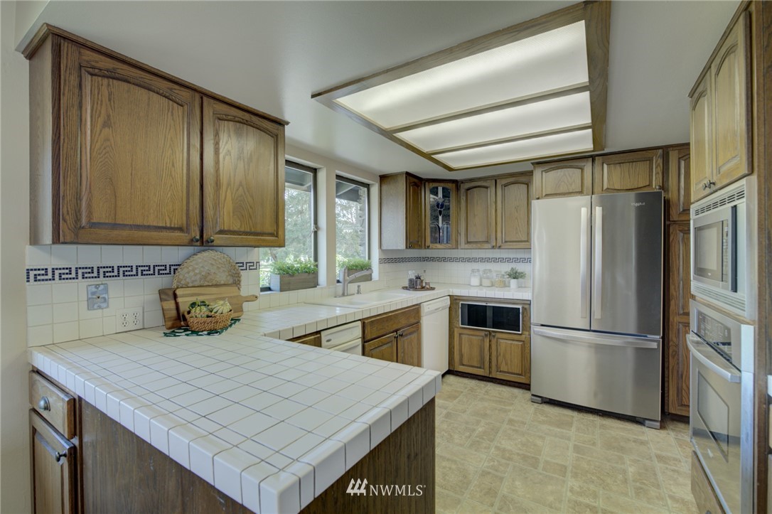 19415 Southeast 141st Street Renton, WA 98059 - Photo 23 of 39 a kitchen with stainless steel appliances a stove refrigerator sink and cabinets