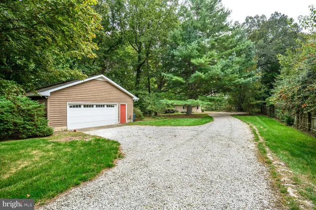 a view of a house with a small yard plants and a large tree