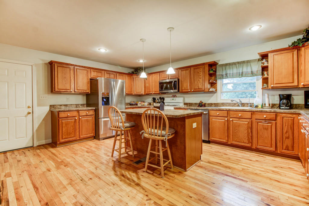 1400 Morgans Mill Road Goodview, VA 24095 - Photo 7 of 21 a kitchen with stainless steel appliances a sink a stove a refrigerator cabinets and wooden floor