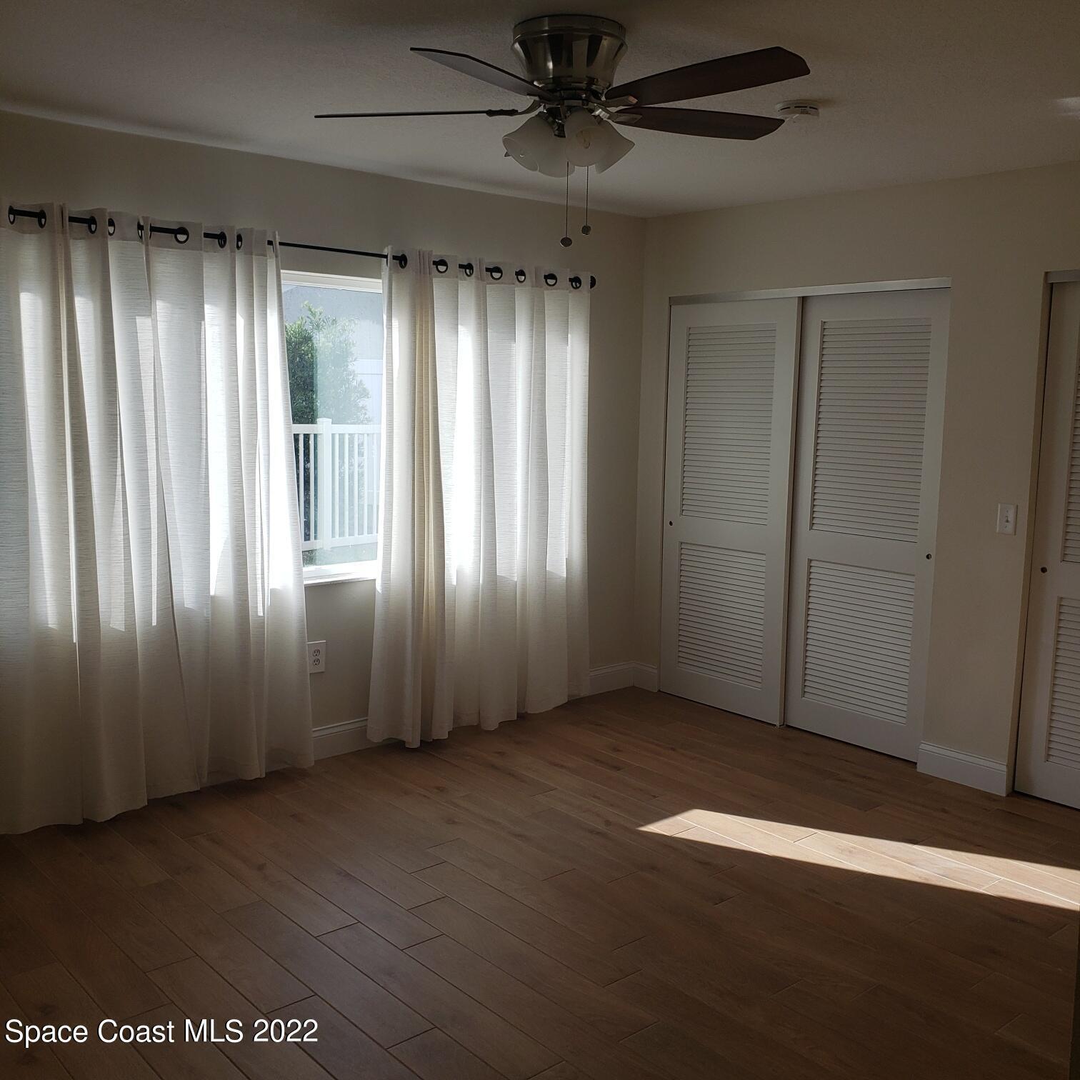 215 Andros Avenue Cocoa Beach, FL 32931 - Photo 23 of 55 an empty room with wooden floor and windows