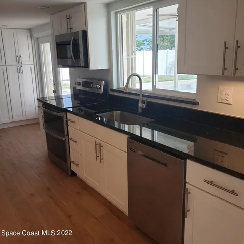 a kitchen with granite countertop a sink and cabinets