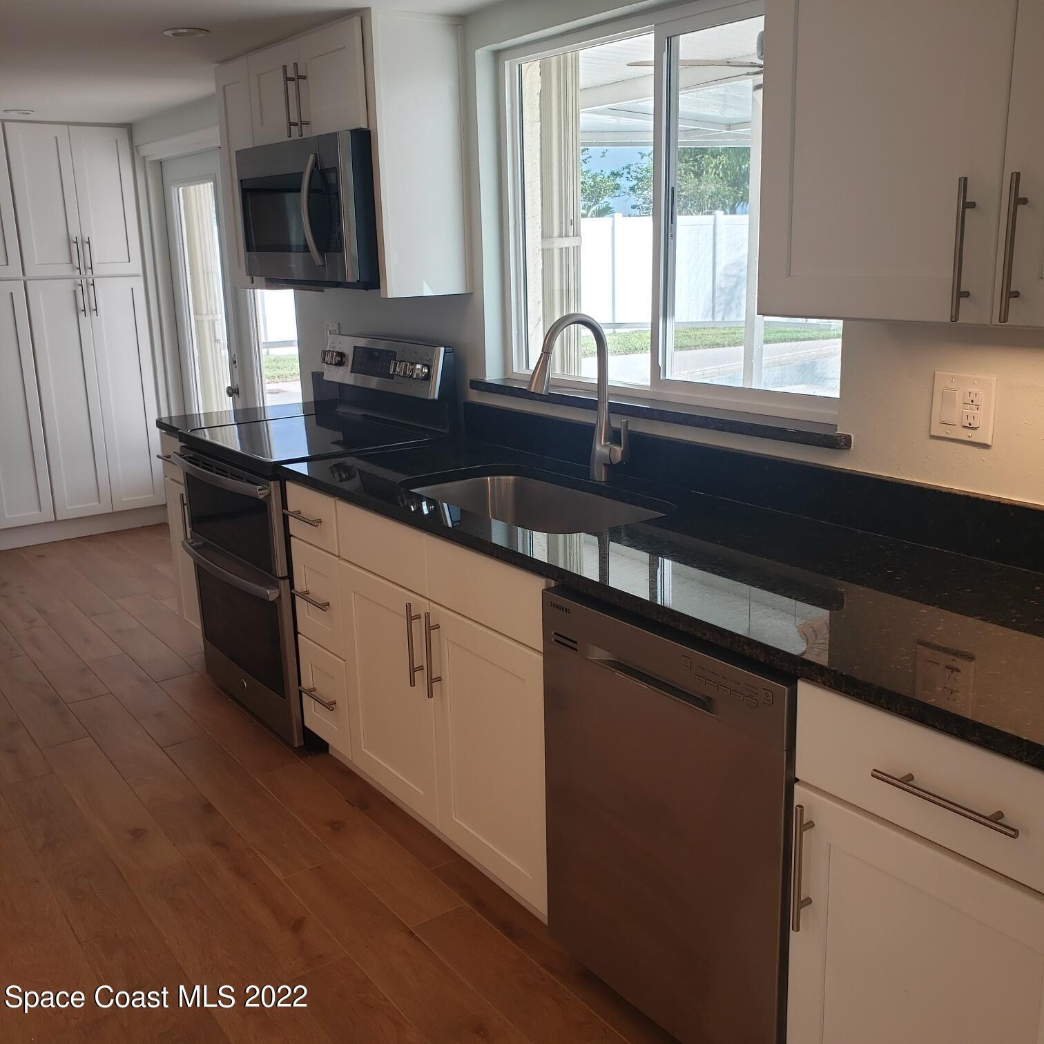 215 Andros Avenue Cocoa Beach, FL 32931 - Photo 26 of 55 a kitchen with granite countertop a sink a stove and cabinets