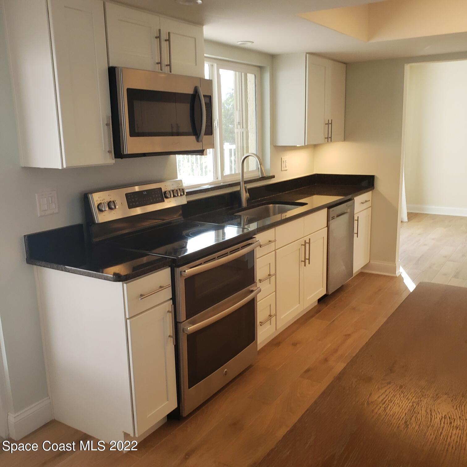 215 Andros Avenue Cocoa Beach, FL 32931 - Photo 30 of 55 a kitchen with stainless steel appliances a stove a microwave a sink and cabinets