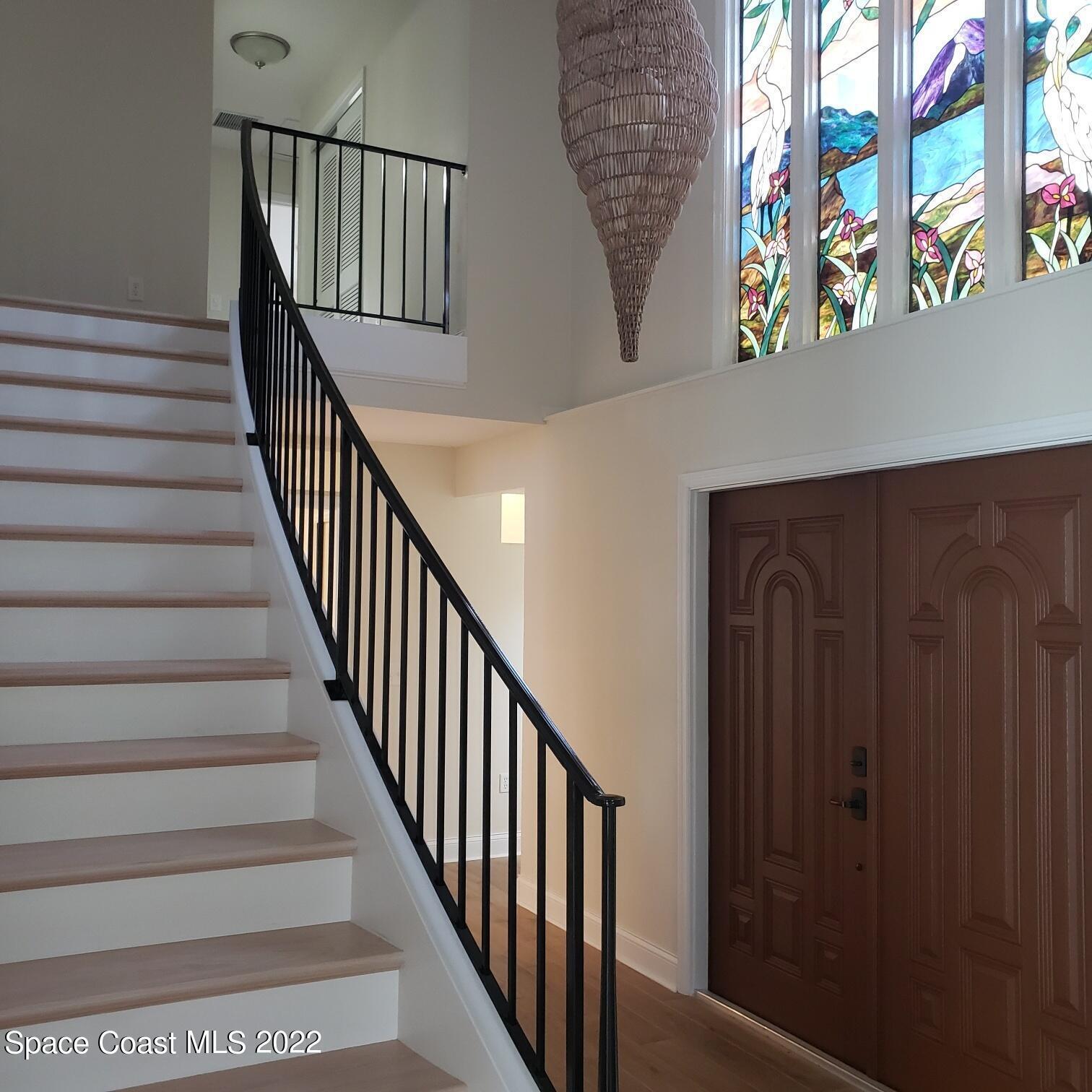 215 Andros Avenue Cocoa Beach, FL 32931 - Photo 39 of 55 a view of staircase with lots of frames on wall and a window