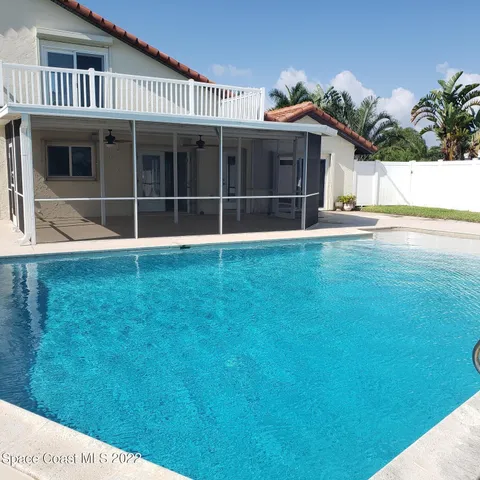 a view of a swimming pool with a lawn chairs under palm trees