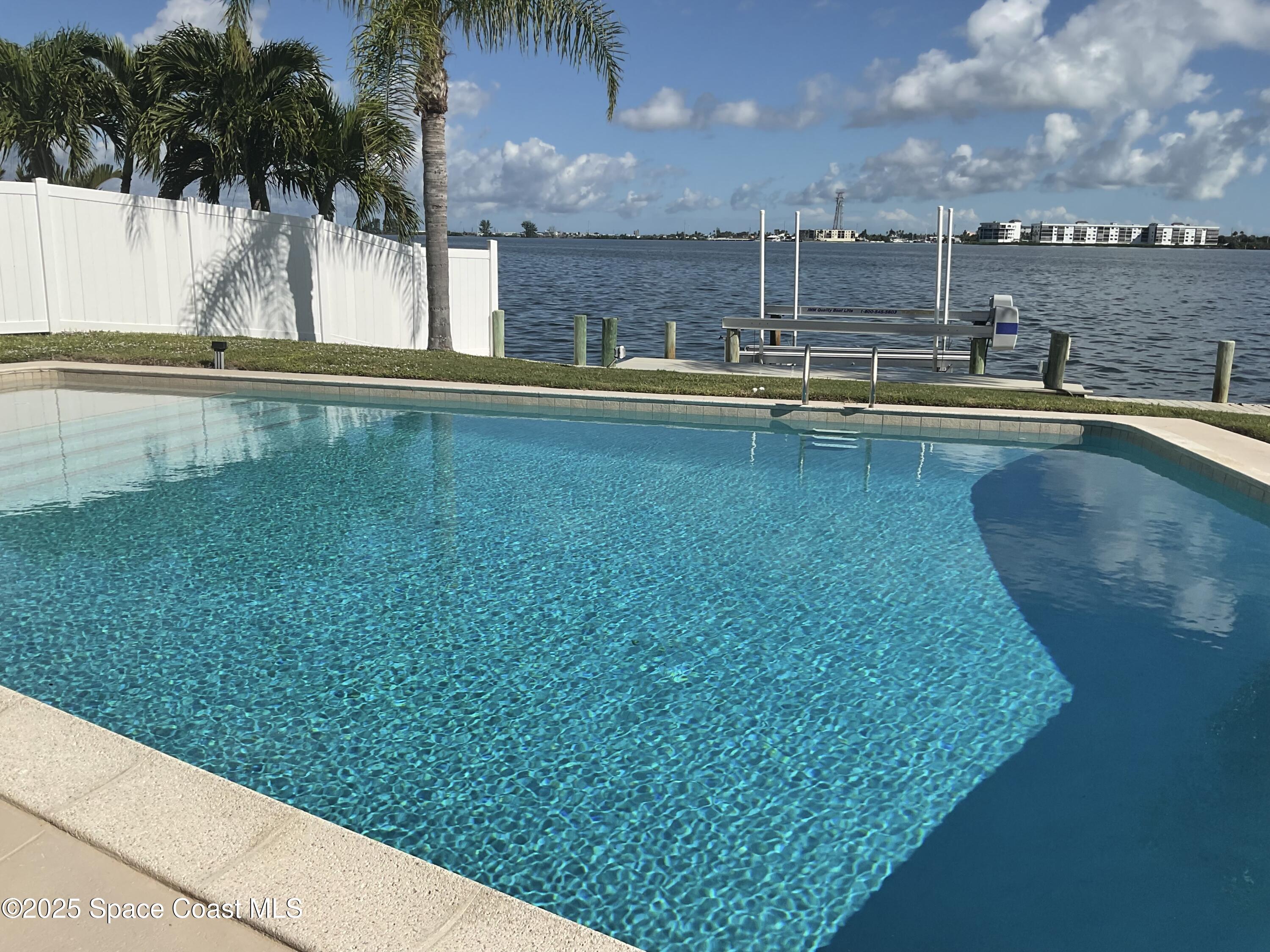 215 Andros Avenue Cocoa Beach, FL 32931 - Photo 53 of 53 a view of a swimming pool with a lawn chairs under palm trees