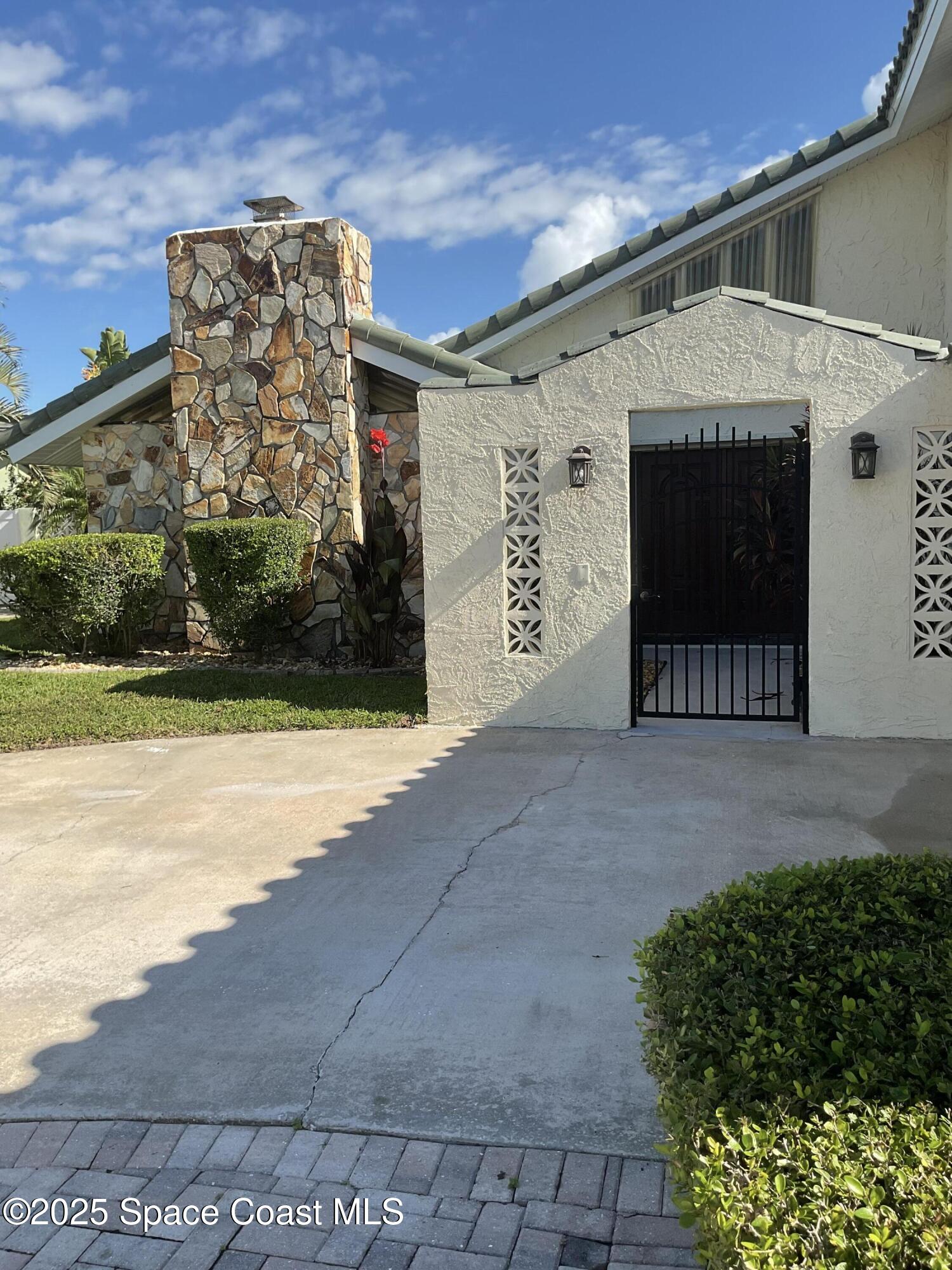 215 Andros Avenue Cocoa Beach, FL 32931 - Photo 7 of 55 a front view of a house with a yard and garage
