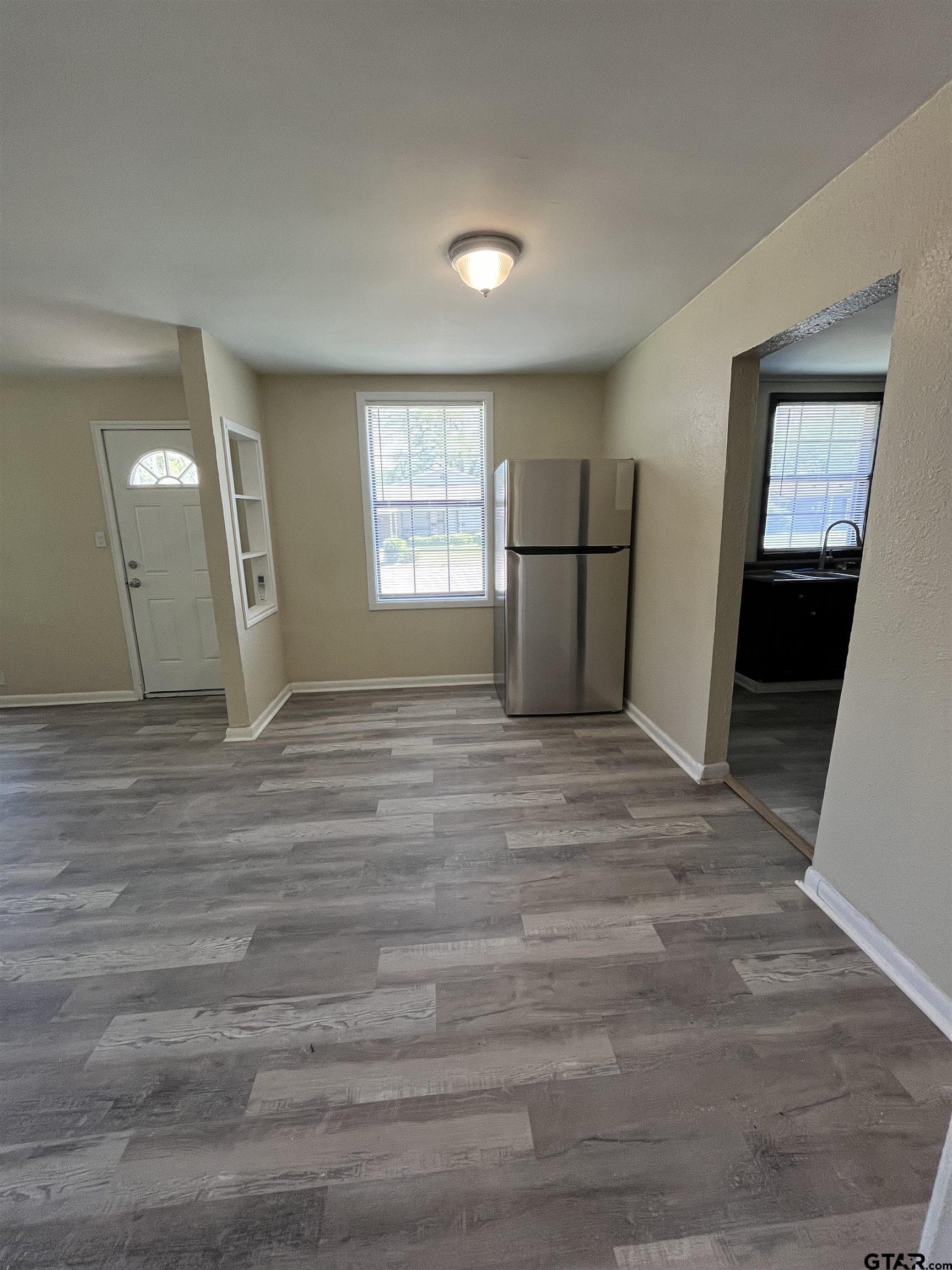 3312 North Luberta Street Tyler, TX 75702 - Photo 5 of 8 a view of an empty room with window and wooden floor