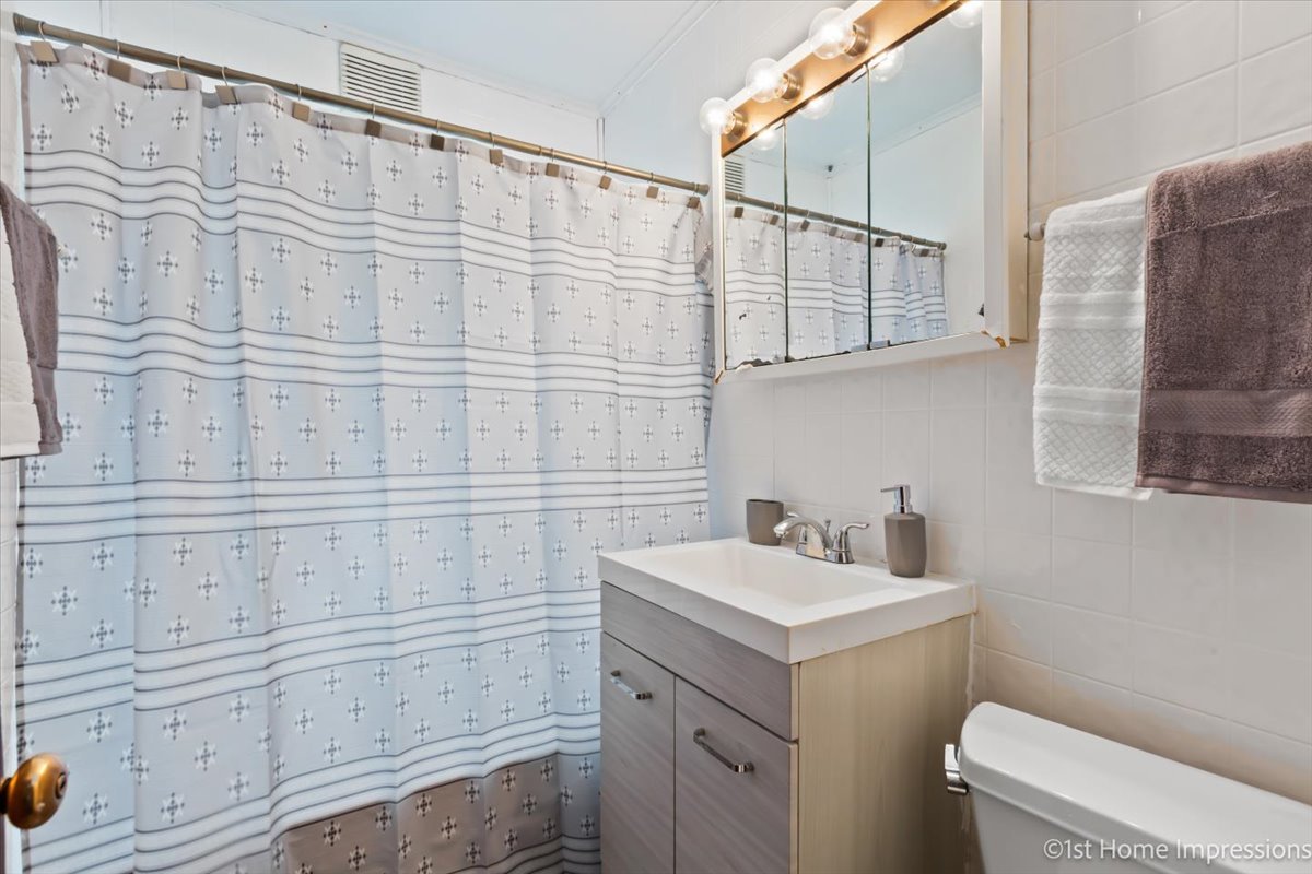 2425 South 13th Avenue Broadview, IL 60155 - Photo 8 of 13 a bathroom with a sink a toilet and shower curtain