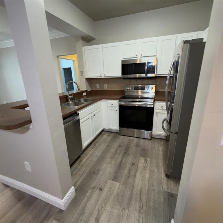 12861 Madison Pointe Circle, Unit 101 Orlando, FL 32821 - Photo 7 of 30 a kitchen with granite countertop a refrigerator stove and microwave