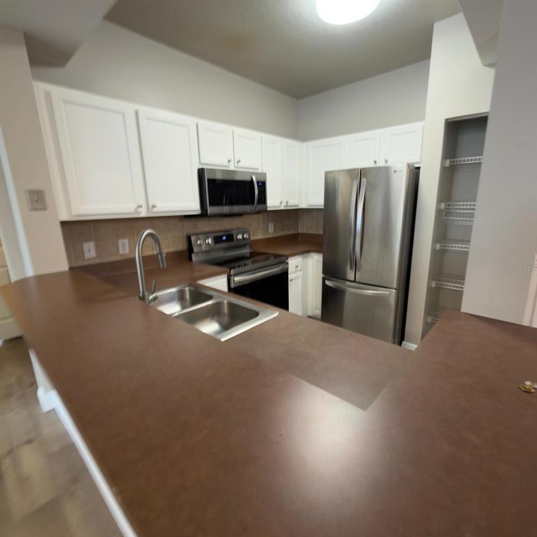 12861 Madison Pointe Circle, Unit 101 Orlando, FL 32821 - Photo 8 of 30 a kitchen with stainless steel appliances a refrigerator a stove a sink a microwave and a refrigerator