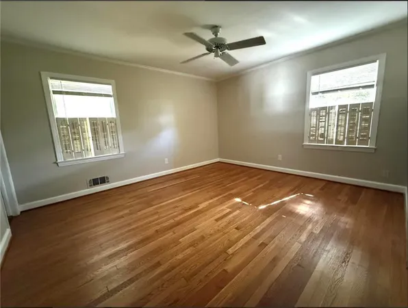 a view of an empty room with wooden floor and a window