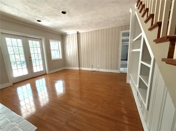a view of an empty room with wooden floor and windows