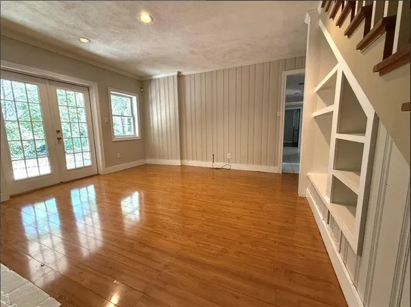 a view of an empty room with wooden floor and a window