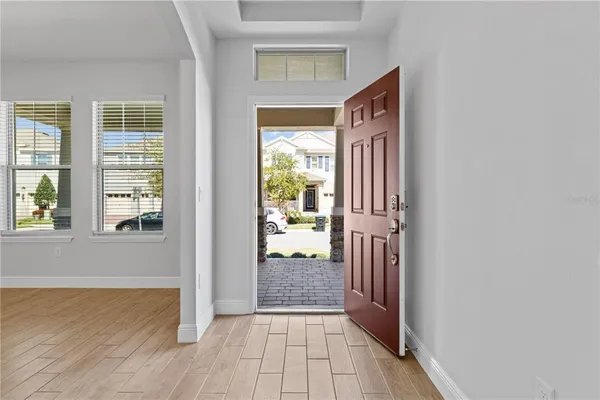 an empty room with wooden floor chandelier and windows