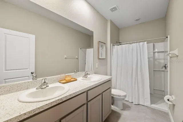 a bathroom with a double vanity sink toilet and shower