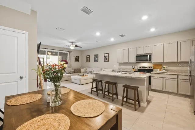 a open dining room with stainless steel appliances kitchen island granite countertop a table and chairs in it