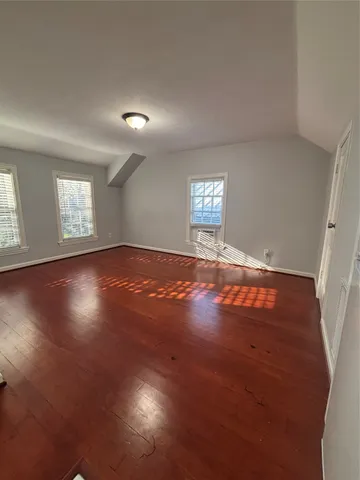 an empty room with wooden floor and windows in it