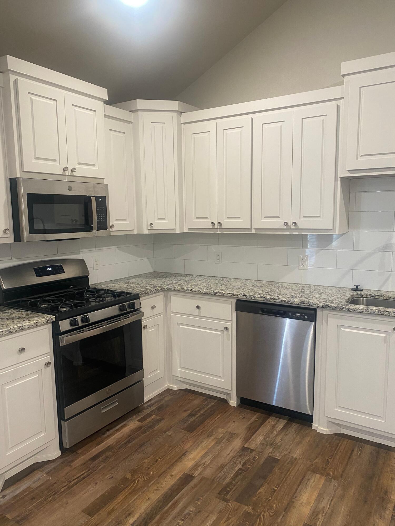 1609 Avenue O, Unit B Shallowater, TX 79363 - Photo 3 of 12 a kitchen with granite countertop white cabinets and stainless steel appliances