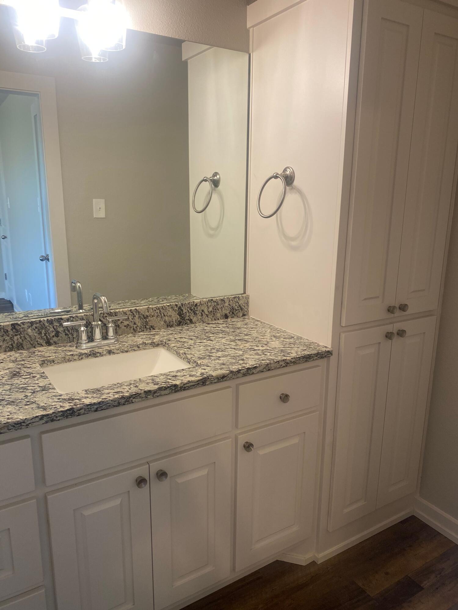 1609 Avenue O, Unit B Shallowater, TX 79363 - Photo 8 of 12 a bathroom with a granite countertop sink and mirror