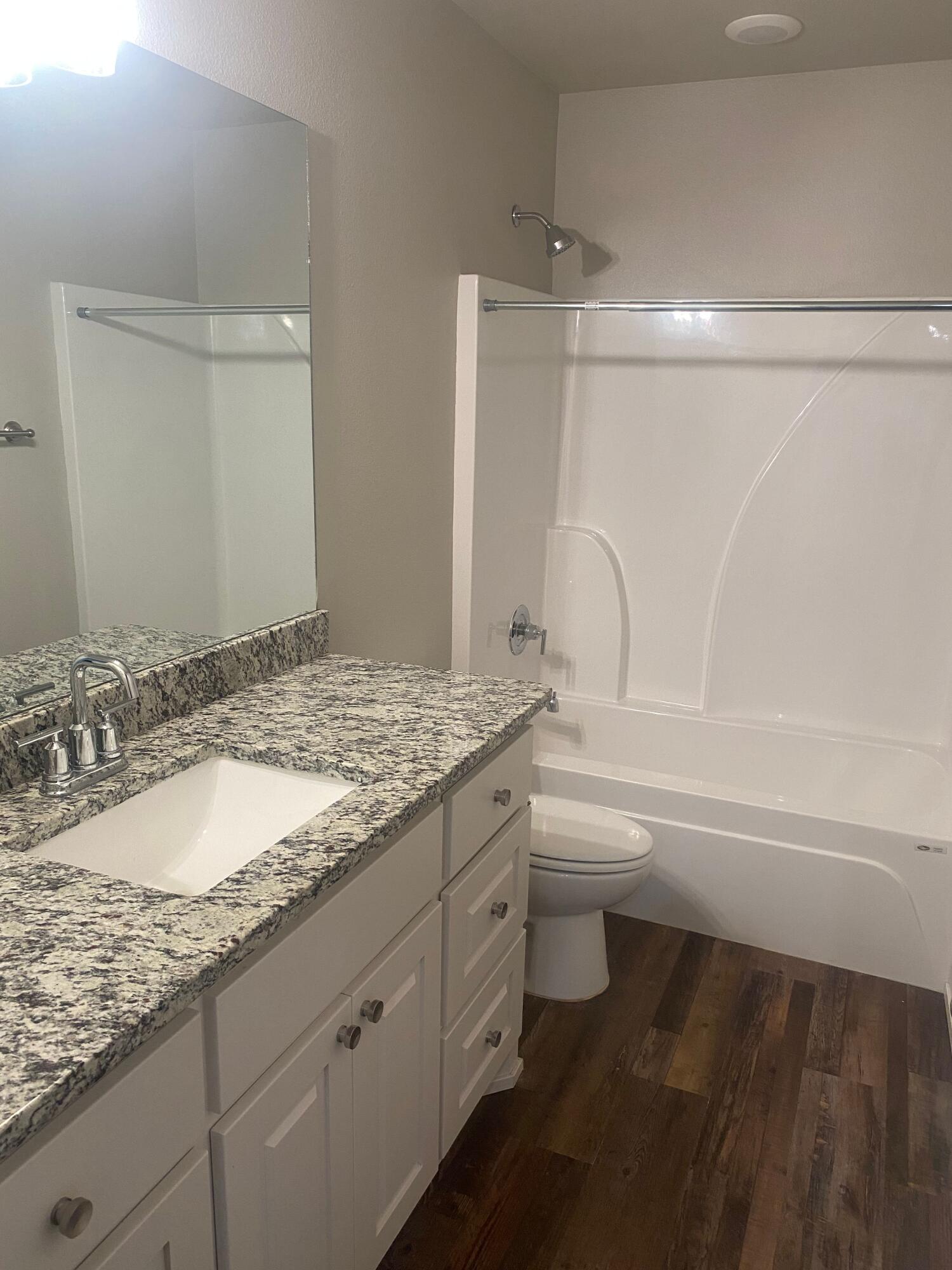 1609 Avenue O, Unit B Shallowater, TX 79363 - Photo 10 of 12 a bathroom with a granite countertop sink toilet and a bathtub
