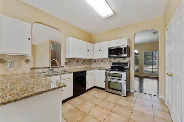 a kitchen with stainless steel appliances granite countertop a refrigerator a stove and white cabinets