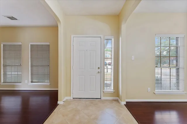an empty room with wooden floor and windows