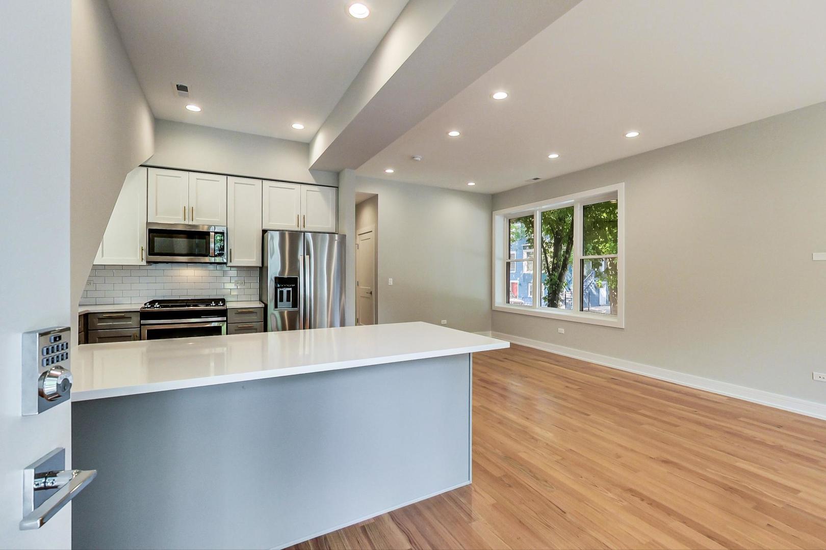 3534 West Wrightwood Avenue, Unit 1F Chicago, IL 60647 - Photo 7 of 18 a large kitchen with stainless steel appliances a large counter top and a stove top oven